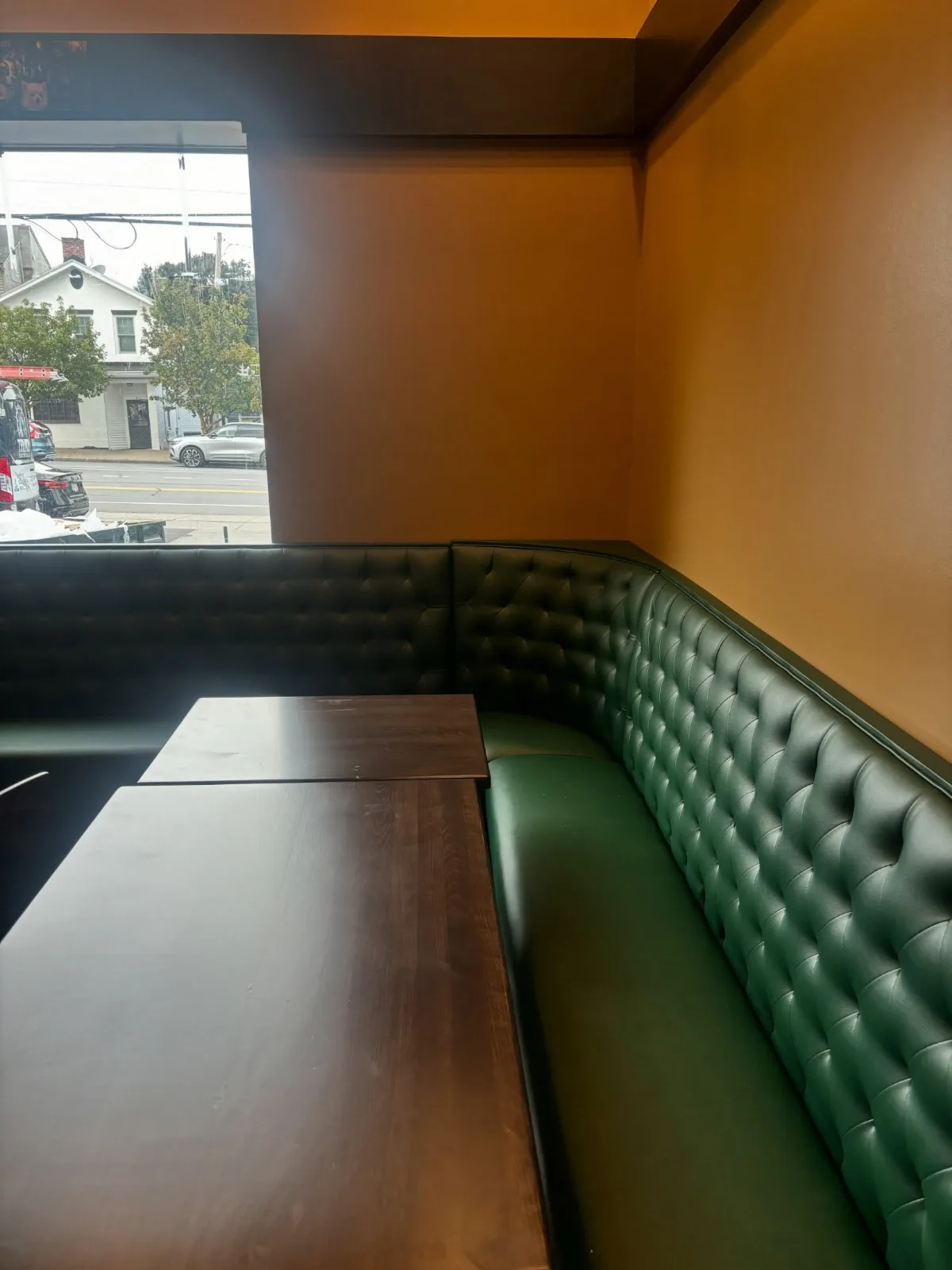A corner booth in green tufted leather beside a window onto State Street
