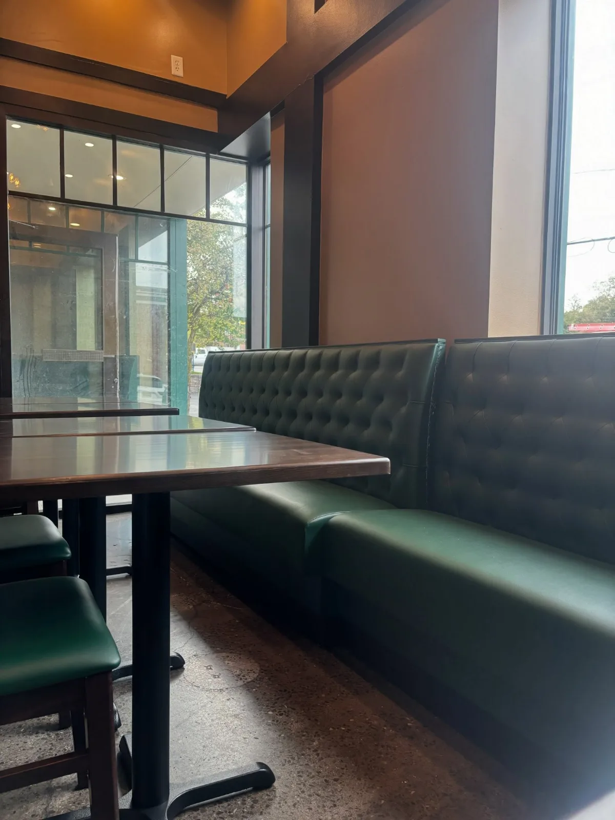 A booth and tables beside the glass entrance