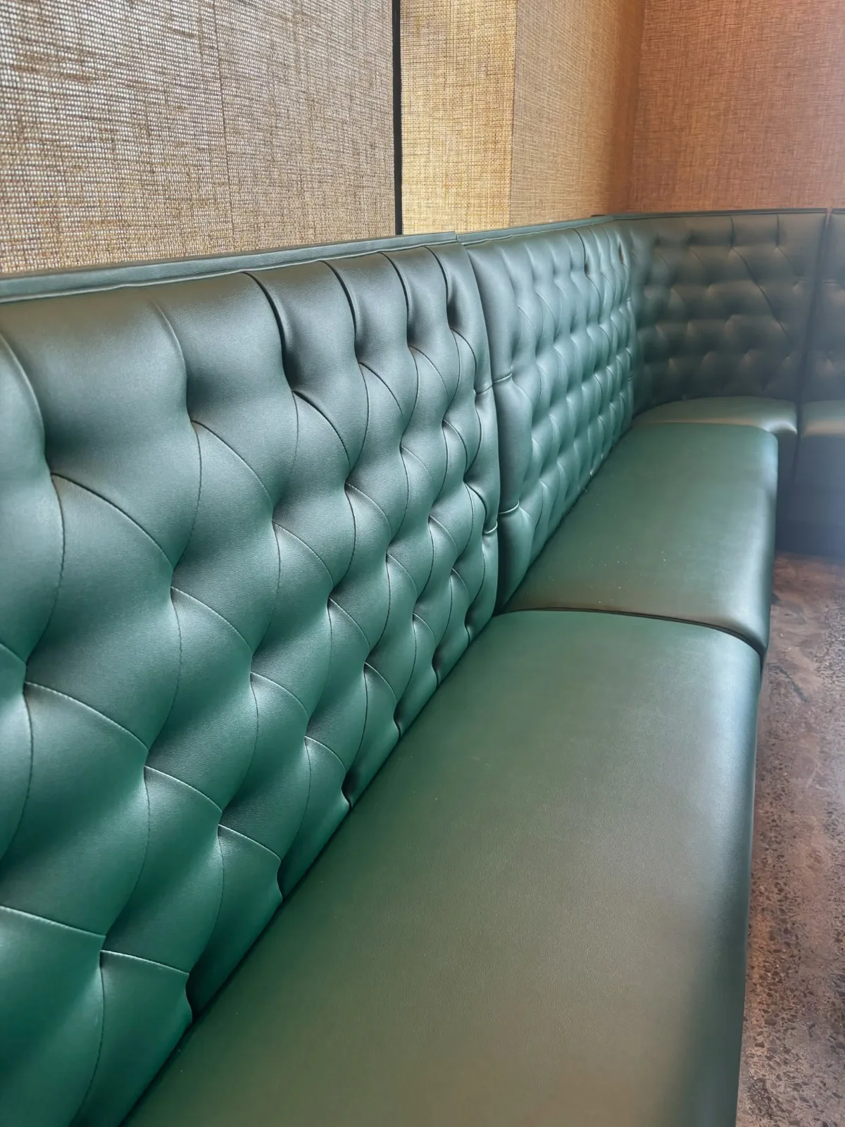 A long booth in green tufted leather