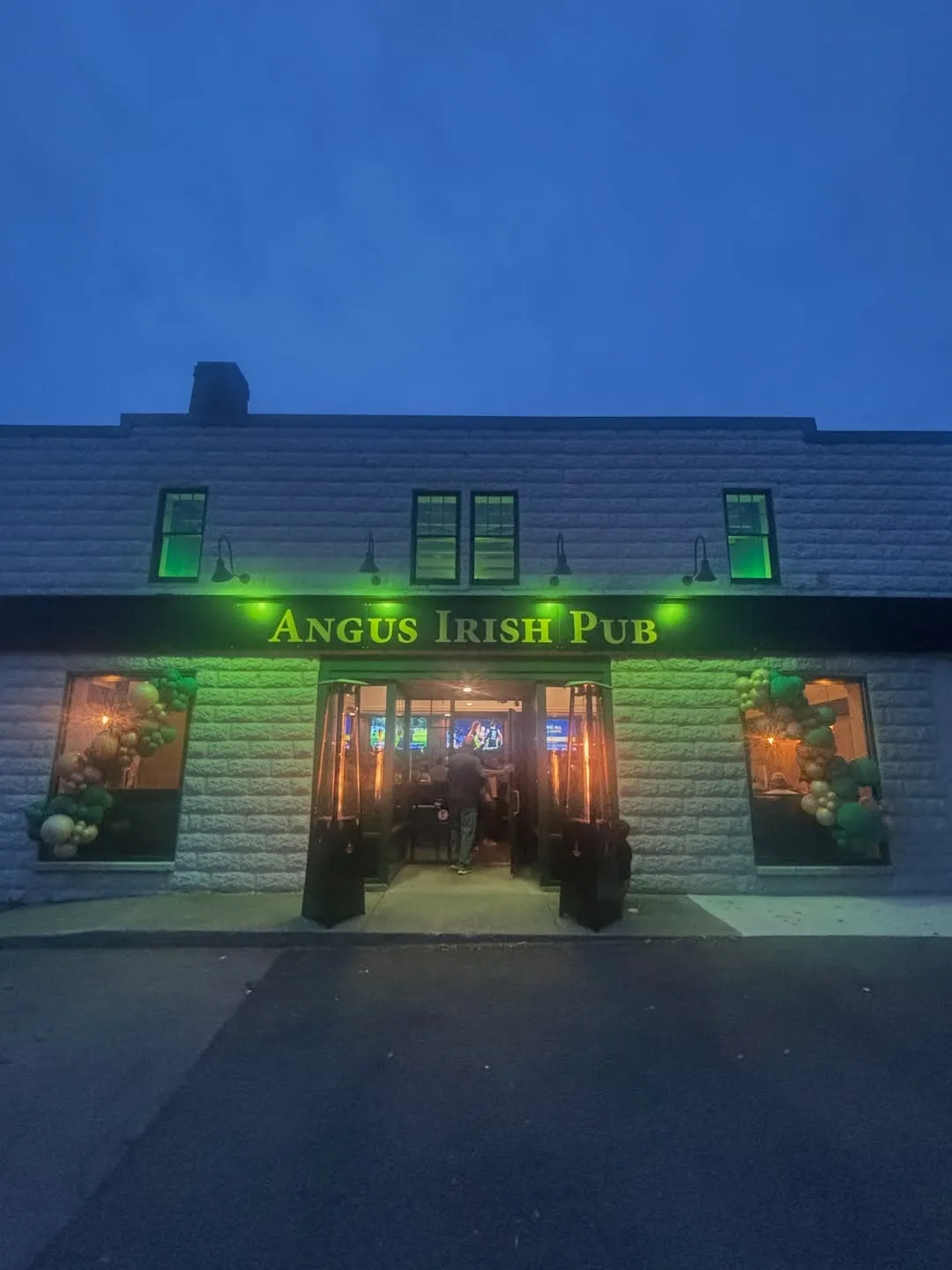 The front of the pub at dusk, the doors open and balloons in the windows